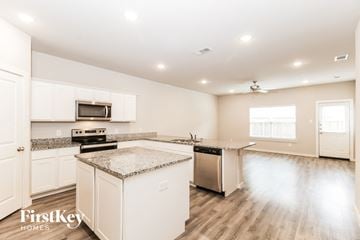 Lewisville house for rent - a kitchen with white cabinets and marble counter tops