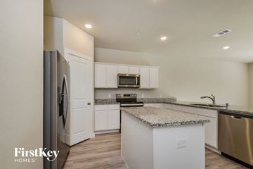 Lewisville house for rent - a kitchen with white cabinets and granite counter tops and stainless steel appliances