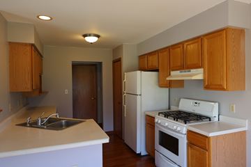Merrillville house for rent - a kitchen with white appliances and wooden cabinets