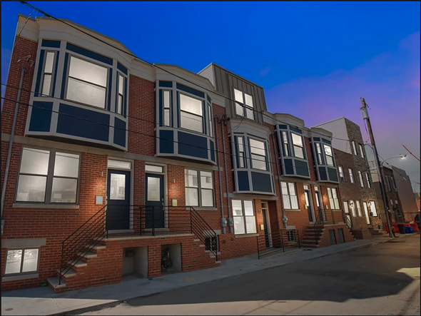 Philadelphia apartment for rent - a row of brick apartment buildings on a city street at night