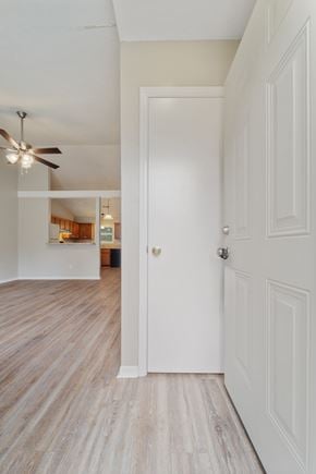 Jacksonville house for rent - A white door is in a hallway with wood flooring and a ceiling fan.