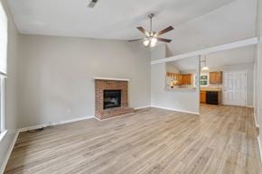 Jacksonville house for rent - A living room with a fireplace and a ceiling fan.