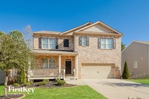 Dallas house for rent - A house with a garage and a tree in front of it.