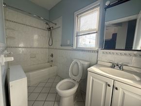 Cranford apartment for rent - A white toilet sits in a bathroom with a white sink and a window.