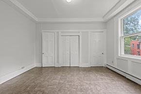 Plainfield apartment for rent - A room with white walls and a large window with a view of a red building outside.