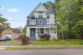 Plainfield apartment for rent - A blue house with a white porch and a grey car parked in front.