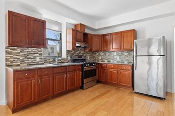 East Orange apartment for rent - A kitchen with wooden cabinets and a stone backsplash.