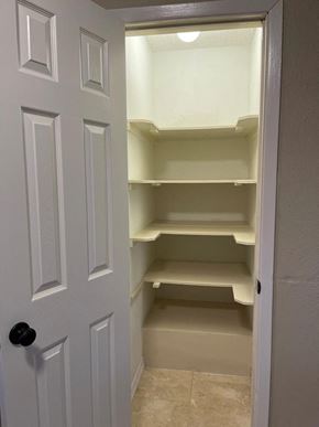 Snyder house for rent - A white door with a black handle is open to a small pantry with shelves.