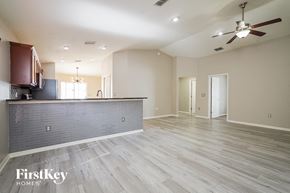 Winter Haven house for rent - an empty living room with a kitchen and a ceiling fan