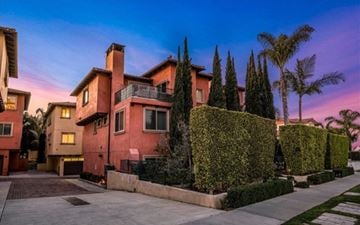 Redondo Beach house for rent - A house with a red facade is surrounded by greenery and trees.