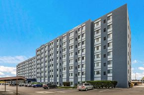 Madison Heights apartment for rent - A large grey building with a parking lot in front.