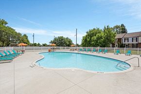 Sterling Heights apartment for rent - A large outdoor swimming pool surrounded by lounge chairs and trees.