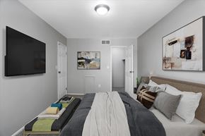Sterling Heights apartment for rent - A bedroom with a bed in the center and a painting on the wall.