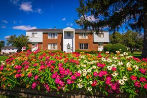 Warren apartment for rent - A house with a white door and windows is surrounded by a flower bed.