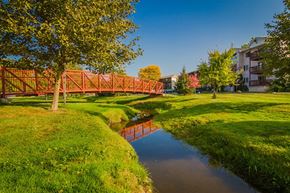 Williamston apartment for rent - A red bridge crosses a small river in a grassy area.