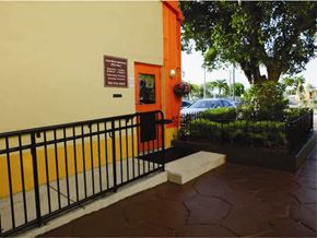 Miami apartment for rent - the entrance to a building with a black railing and a tree