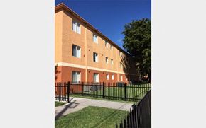 Homestead apartment for rent - the side of a brick building with a yard and a fence
