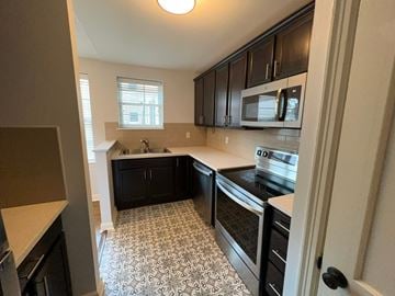 Little Rock apartment for rent - a kitchen with black cabinets and a black and white tile floor