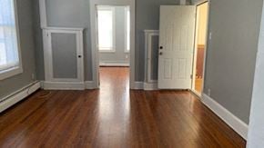 Hartford apartment for rent - an empty living room with wooden floors and a white door