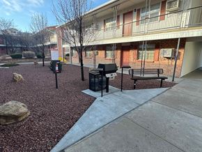 Gallup apartment for rent - A courtyard with a bench, a trash can, and a tree.