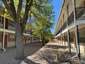 Gallup apartment for rent - A tree in the middle of a pathway between two buildings.