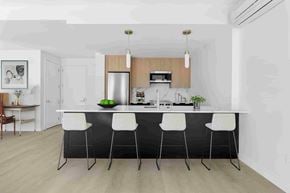 Brooklyn apartment for rent - A modern kitchen with a white countertop and black bar stools.