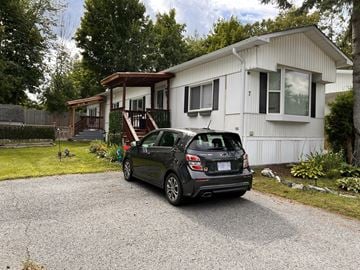 Stittsville house for rent - A car is parked in front of a white house with a brown roof.