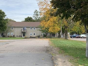 Kentville apartment for rent - A tree with yellow leaves is in front of a grey building.