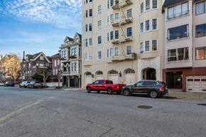 San Francisco apartment for rent - A red car is parked on the street in front of a white building.