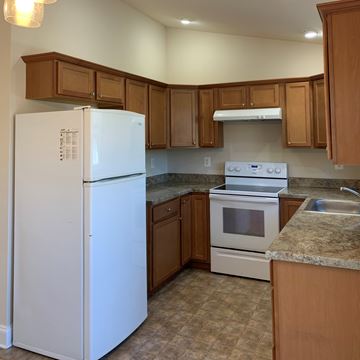 Laurel apartment for rent - A white refrigerator stands in a kitchen with brown cabinets.