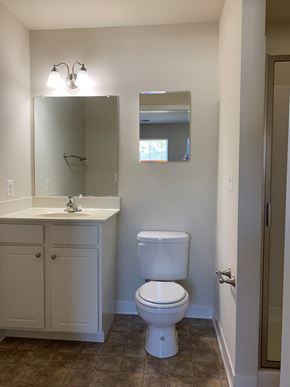 Laurel apartment for rent - A white toilet sits in a bathroom next to a sink and medicine cabinet.
