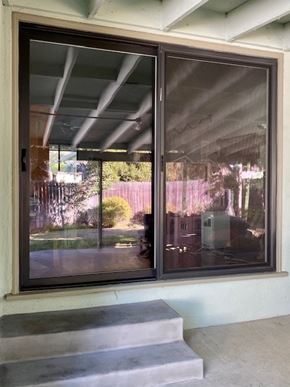 Woodland Hills apartment for rent - A sliding glass door with a reflection of a building and trees.