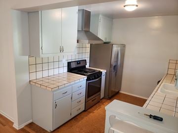 Woodland Hills apartment for rent - A kitchen with white cabinets and a tiled backsplash.
