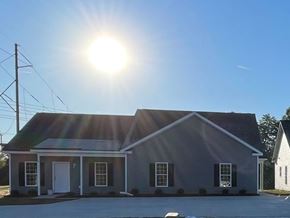 Wilson apartment for rent - A house with a grey roof and white door is bathed in sunlight.