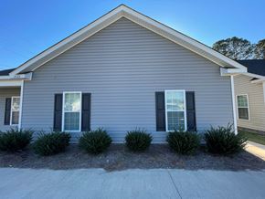 Wilson apartment for rent - A house with a grey siding and two windows with black shutters.