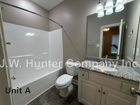 Wilson apartment for rent - A bathroom with a toilet, sink, and mirror.