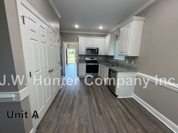Wilson apartment for rent - A kitchen with white cabinets and a wooden floor.