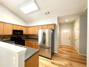 Simpsonville house for rent - a kitchen with wooden cabinets and a stainless steel refrigerator