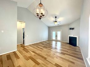 Simpsonville house for rent - a large living room with a hardwood floor and a chandelier