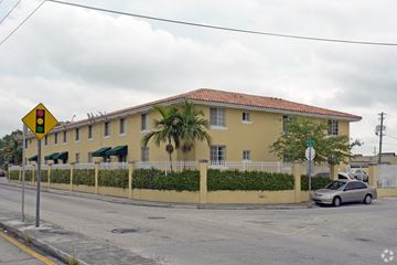 Miami apartment for rent - A yellow building with a red roof and a car parked in front.