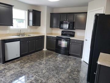 Brownsville house for rent - a kitchen with black cabinets and stainless steel appliances