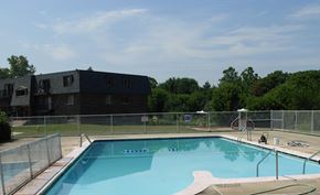 West Chicago apartment for rent - A swimming pool with a fence around it and a building in the background.