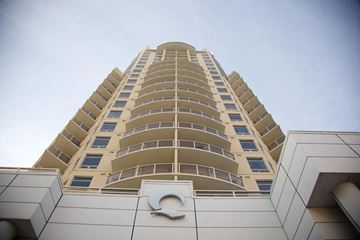 Edmonton apartment for rent - A tall building with a white facade and a large circular logo on the bottom.