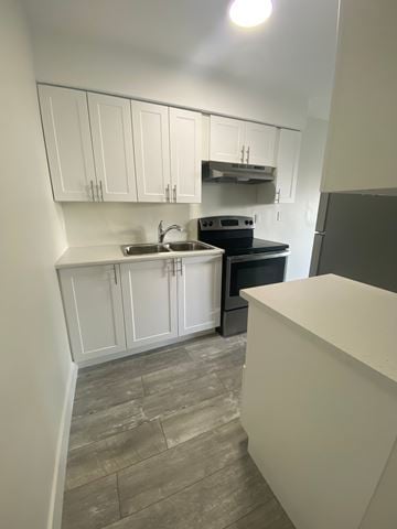 Nanaimo apartment for rent - A kitchen with white cabinets and a black stove top oven.