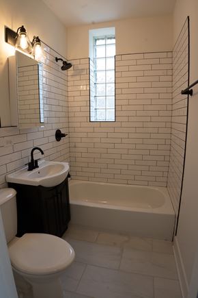 Chicago apartment for rent - A white toilet sits next to a sink in a bathroom with a black trash can.
