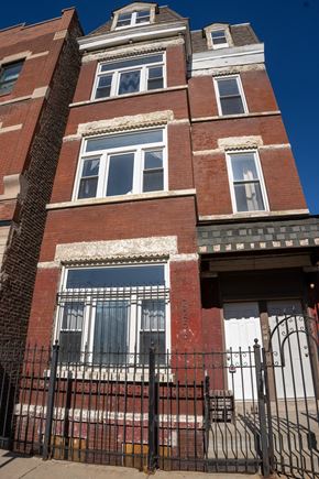 Chicago apartment for rent - A red brick building with a black iron fence in front.