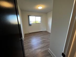 Nanaimo apartment for rent - A room with a black door and a window with a view of trees outside.