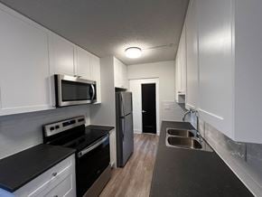Nanaimo apartment for rent - A kitchen with black countertops and white cabinets.