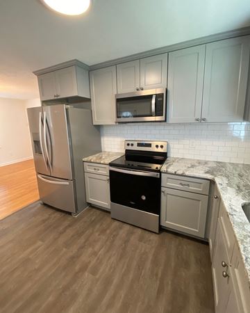 Fayetteville house for rent - a kitchen with white cabinets and stainless steel appliances