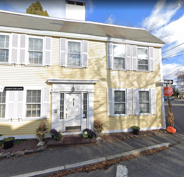 Marblehead apartment for rent - the front of a yellow house with white shutters and a stop sign
